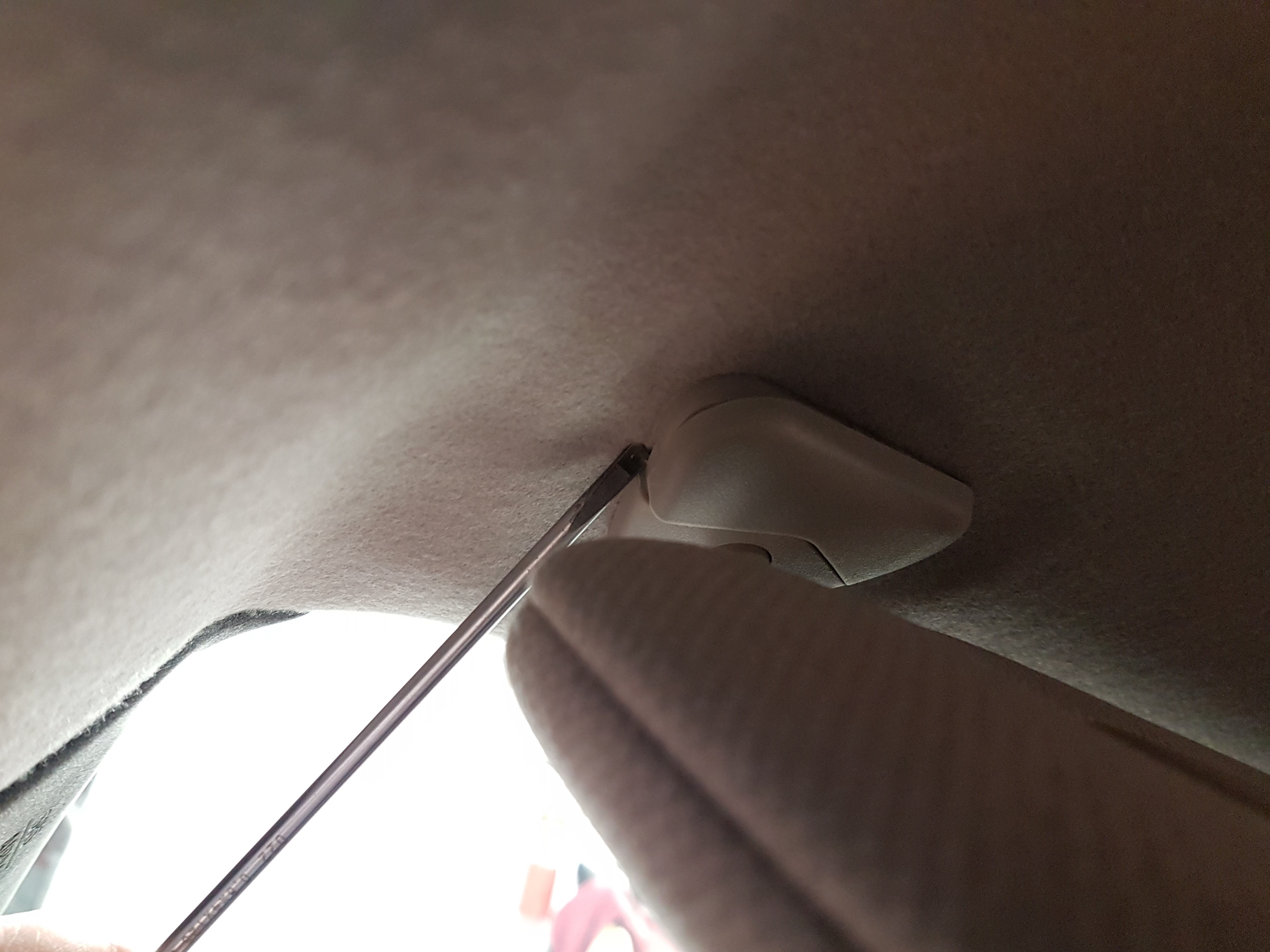 Removing Nissan Leaf sun visor cover with a flathead screwdriver