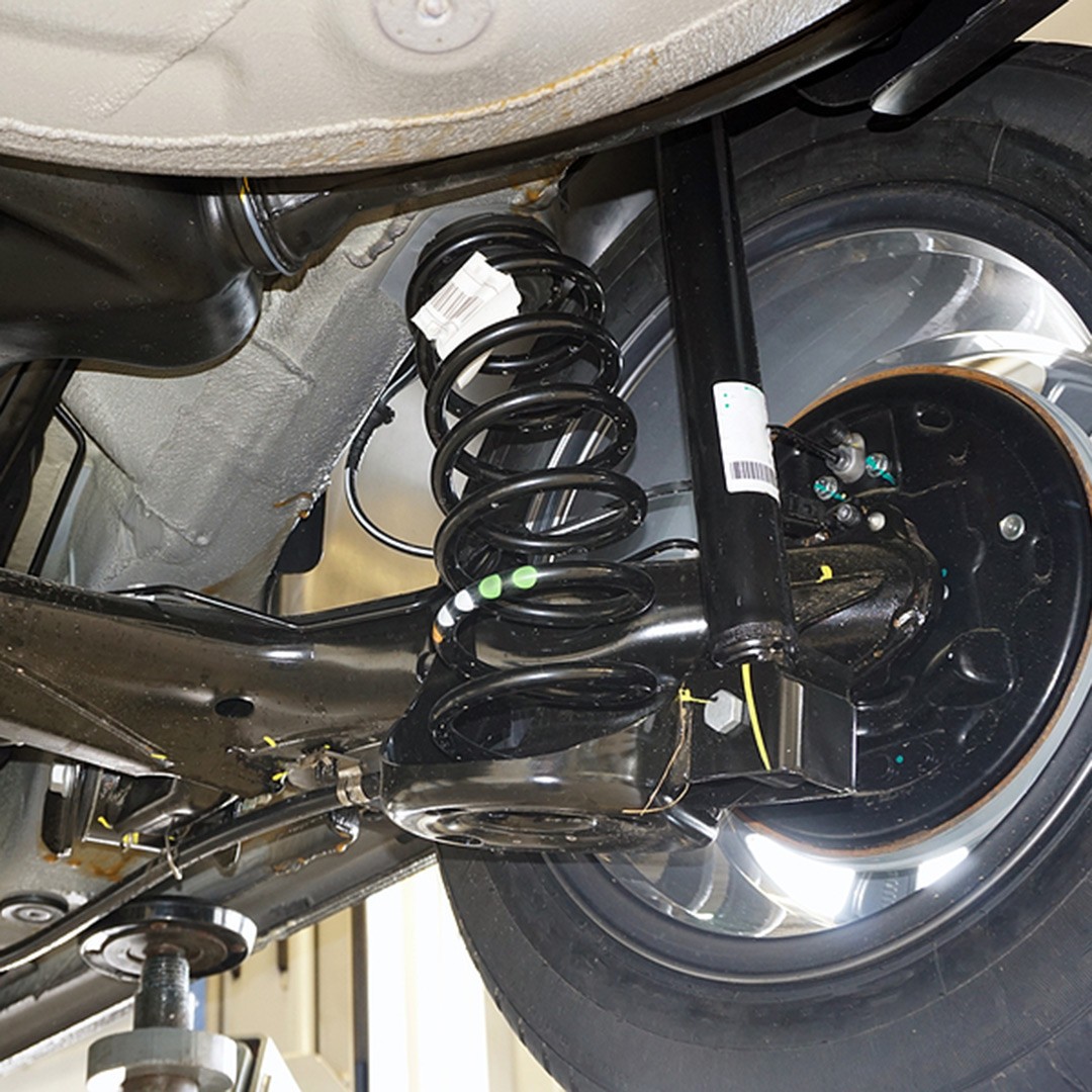 Close-up of modern car rear suspension components including shocks, springs and control arms.