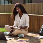 african girl sitting in her garden, noting down which are the english langage levels in the CEFR