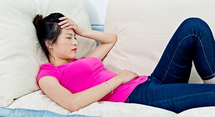 Woman experiencing heavy period pain, highlighting the services of Total Woman at Norton Women's Care for menorrhagia treatment.