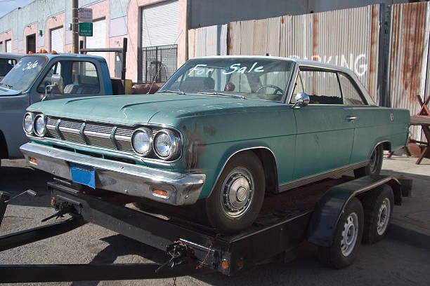 Teal car on tow truck, indicating potential for part salvage and sale.