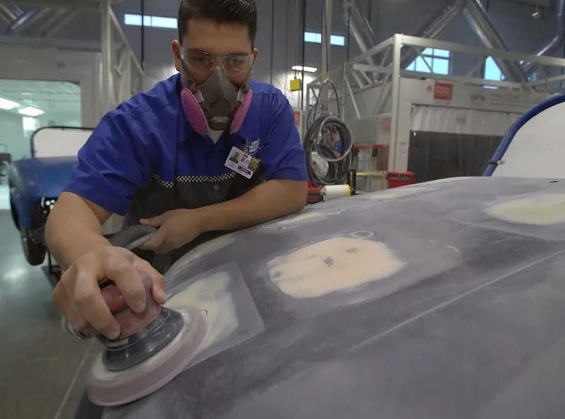 Close up of hands grinding down a black car part